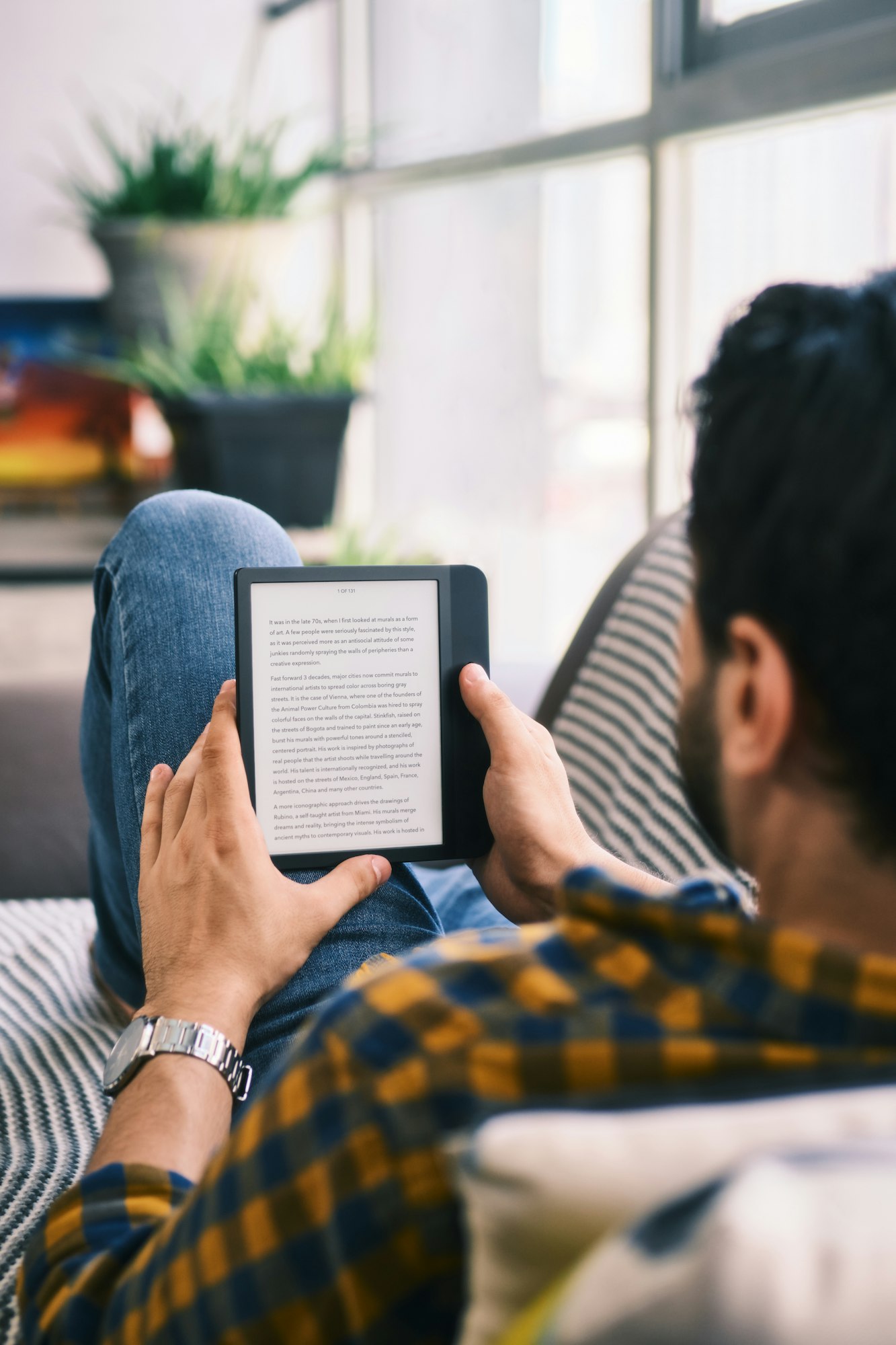 Young Man Reading Ebook With Ereader On Couch